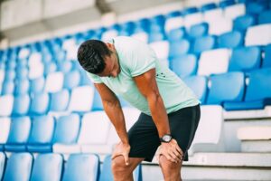 Tired exhausted young man catching breath after hard training